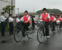 オレンジ色のビブスを着て八幡警察署を出発する「安全守るんジャー！」生徒たち