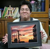 受賞作品「ゆうやけ」の写真を手に笑顔の米田祐二さん