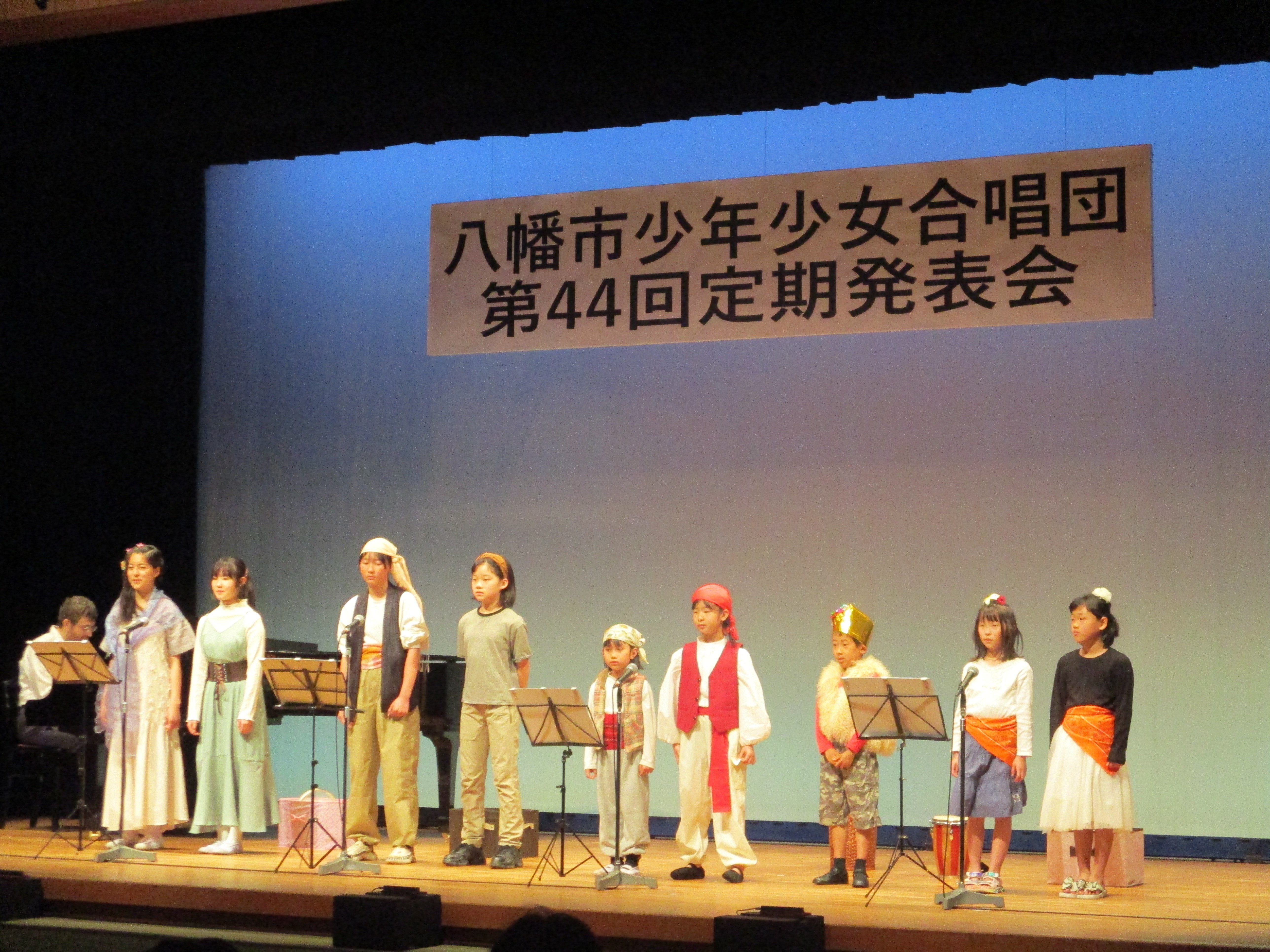 制服を着て歌う合唱団の子どもたち